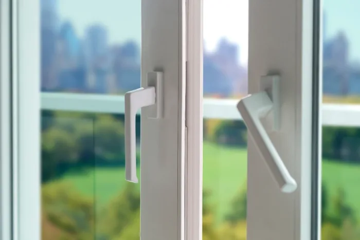 Close-up of two partially open white sliding doors with modern handles, revealing a blurred view of a green landscape and Tampa FL city skyline in the background. The scene is bright and inviting, suggesting a view from a local high-rise apartment or office.